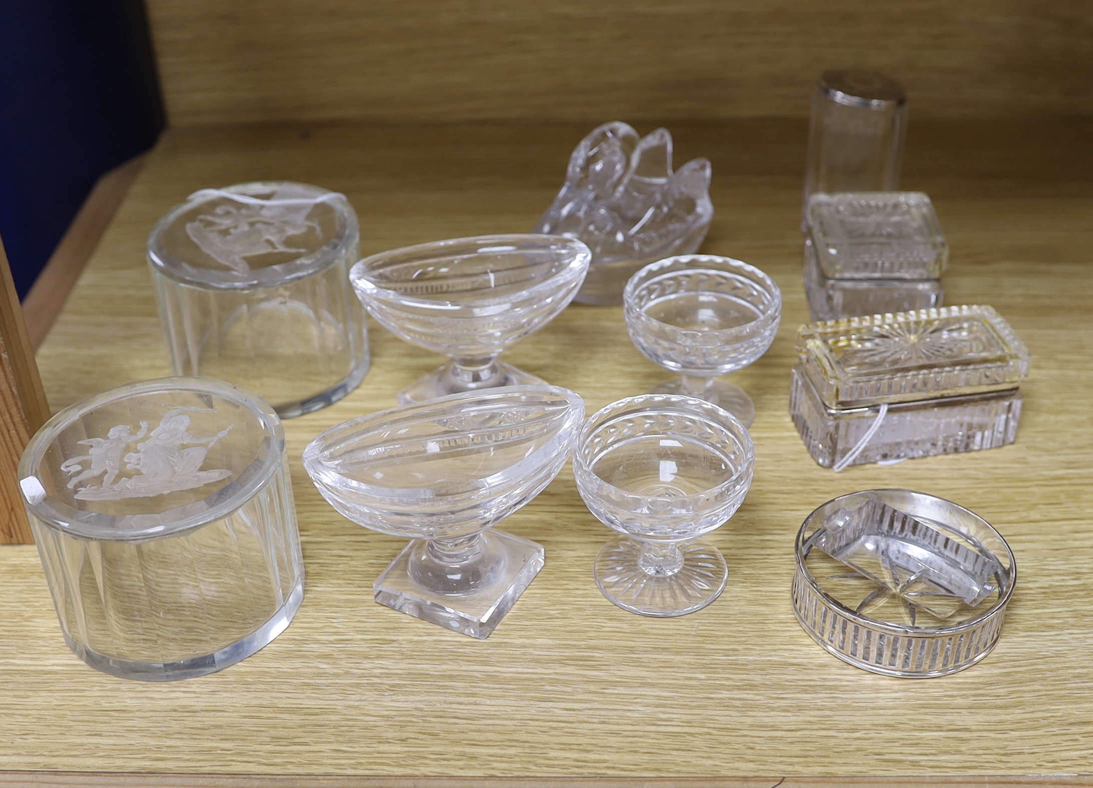 A quantity of glassware to include a pair of cylindrical containers with covers, intaglio engraved scenes to lids, a silver mounted stamp roller, a pair of pedestal salts, etc.